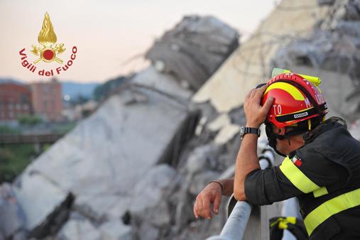 Un vigile del fuoco in un momento di pausa contempla le rovine del ponte Morandi
