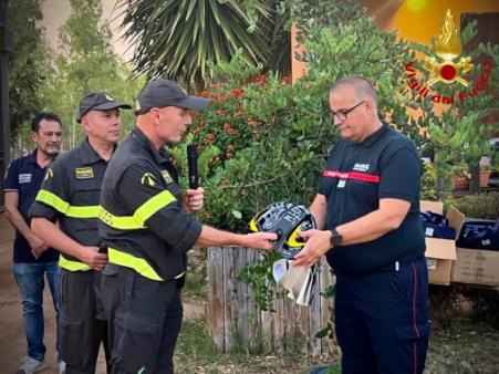 Il Comandante VV.F. di Cagliari consegna un casco firmato ad un membro del team di sicurezza civile francese