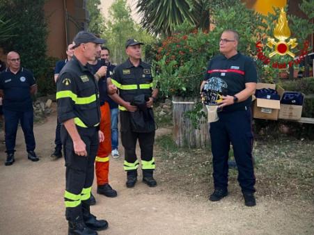 Il Comandante VV.F. di Cagliari consegna un casco firmato ad un membro del team di sicurezza civile francese
