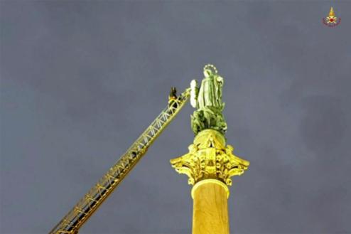 Il Capo reparto più anziano del comando di Roma sale i trenta metri dell'autoscala per deporre l'omaggio floreale dei Vigili del fuoco sul braccio della statua della Madonna in piazza Mignanelli a Roma