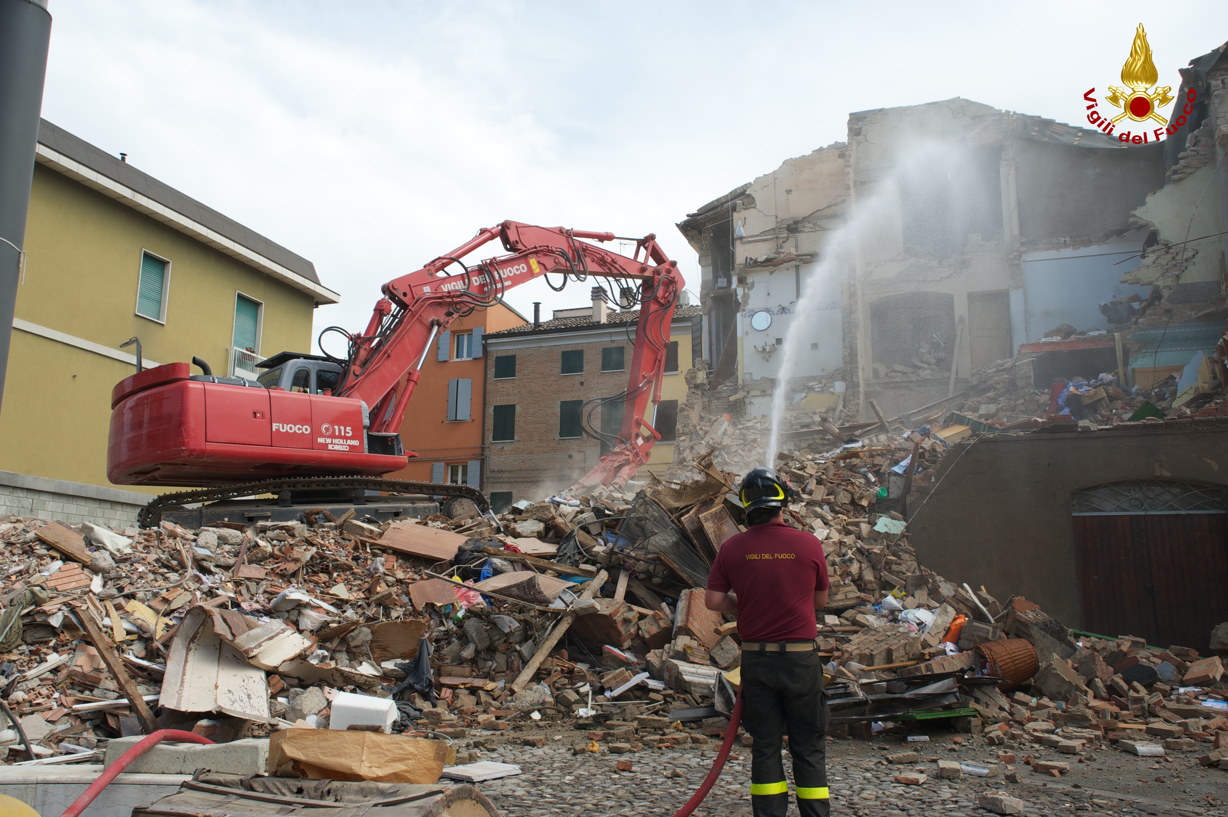Demolizione abitazione in centro a Cavezzo (MO), tramite mezzo speciale VvF Belluno. Vigili del Fuoco mentre bagna le macerie, per catturare la polvere.